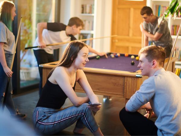 group of young people talking and playing pool