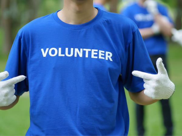 person pointing at t shirt that says volunteer