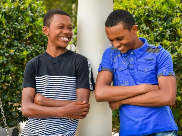 two young boys leaning on a lamp post smiling