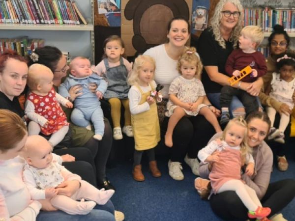 Group of parents or carers with their children sat on their knee