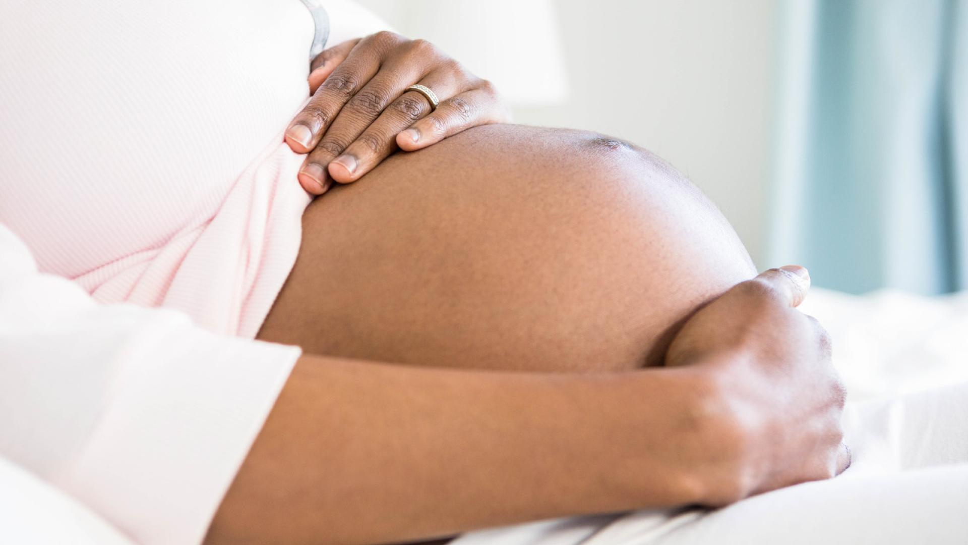 Black lady holding her pregnant tummy 