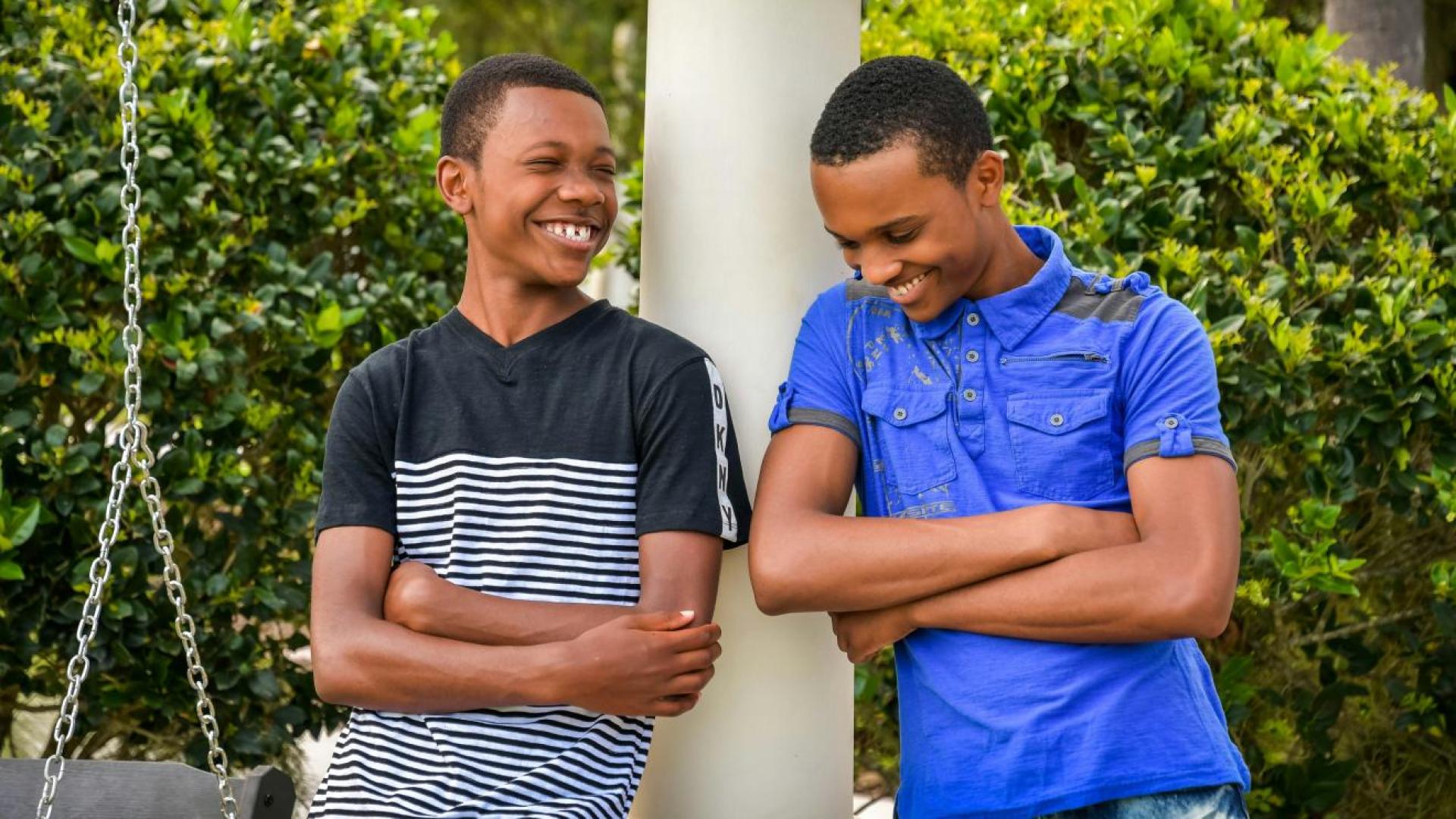 two young boys leaning on a lamp post smiling